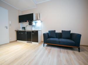 a living room with a blue couch and a kitchen at Main Boardinghouse in Erlenbach am Main