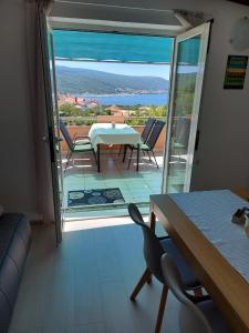a living room with a table and chairs and a balcony at Apartments Mory in Kornić