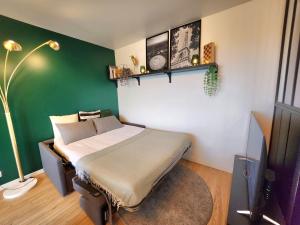 ein Schlafzimmer mit einem Bett und einer grünen Wand in der Unterkunft L'arène du Stade de France - 100 mètres + parking in Saint-Denis