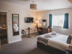um quarto de hotel com uma cama, uma secretária e um espelho em Crossways em Wells