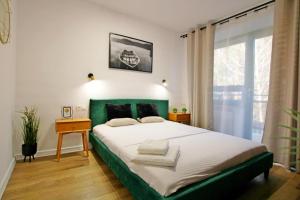 a bedroom with a large bed with a green headboard at Holi Resort in Serock