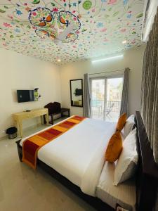 Krishna kottage A Boutique Home Stay في أودايبور: غرفة نوم مع سرير كبير وسقف ملون