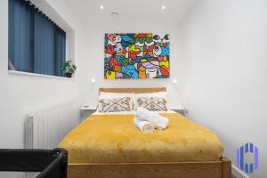 a bedroom with a yellow bed with a painting on the wall at Stylish, Modern 4 bed - Etihad - Games - Parking in Manchester