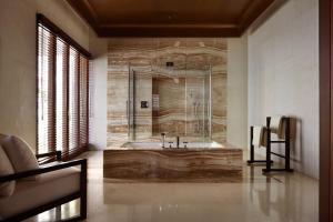 a bathroom with a tub with a stone wall at Bulgari Resort Bali in Uluwatu