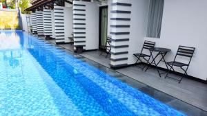 a swimming pool with chairs and a table next to a building at Odaita Hotel Pamekasan Madura in Pademabu