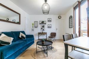 ein Wohnzimmer mit einem blauen Sofa und einem Tisch in der Unterkunft MBA Splendide Appart Diderot 2 - Proche Vincennes in Montreuil