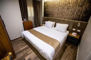 um quarto de hotel com uma cama com lençóis brancos e almofadas em Golden Pyramids Sunrise Hotel no Cairo