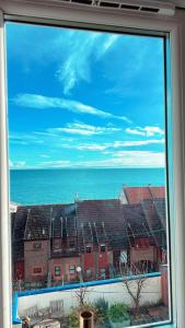 a window with a view of a building and the ocean at Two Bedroom Flat with Sea Views! in Fife