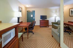 a hotel room with a desk and a living room at Independence Stay Hotel & Suites in Marinette