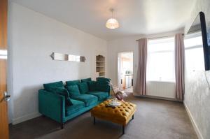 a living room with a green couch and a table at Two Bedroom Flat with Sea Views! in Fife