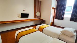 a hotel room with two beds and a flat screen tv at Odaita Hotel Pamekasan Madura in Pademabu