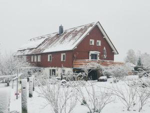 a large red barn with snow on its roof at Ferienwohnung Feldblick in Struppen