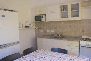a kitchen with white cabinets and a table with chairs at Casa de Playa in Puerto Madryn