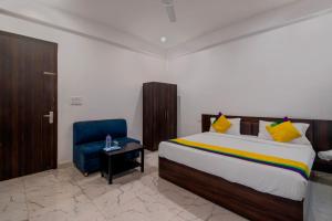 a bedroom with a bed and a blue chair at Itsy By Treebo - Om Pushp Residency in Mathura