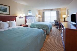 a hotel room with two beds and a flat screen tv at Independence Stay Hotel & Suites in Marinette