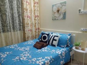 a bed with a blue comforter with the word love on it at Teratak Hannani Maryam Kampar ( Muslim Homestay) in Kampar