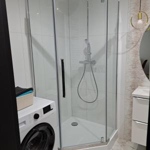a bathroom with a shower and a washing machine at Apartament Grand in Koszalin