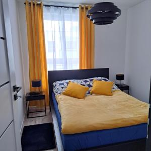 a bed with yellow pillows in a room with a window at Apartament Grand in Koszalin