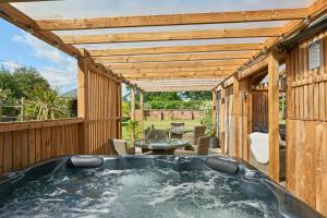 a hot tub on a deck with a pergola at Willington Lodge in Hanmer