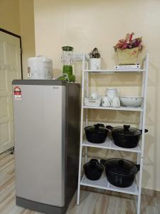 a kitchen with a shelf with bowls and a refrigerator at Teratak Hannani Maryam Kampar ( Muslim Homestay) in Kampar