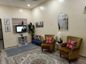 un soggiorno con 2 sedie e una TV di Teratak Hannani Maryam Kampar ( Muslim Homestay) a Kampar