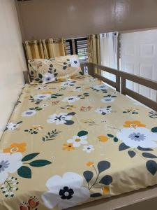 a bed with a blanket with flowers on it at PMPJ Cabin in Lipa