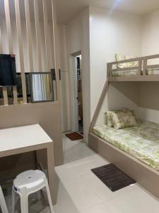 a room with a bunk bed with a desk and a stool at PMPJ Cabin in Lipa