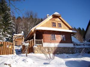 uma cabana de madeira na neve com uma cerca em Hotel Podlesí em Podlesí