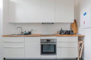 a kitchen with white cabinets and a sink and a stove at Ruime studio in centrum voor 4 in Ghent +4 photos