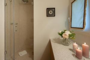 a bathroom with a shower with candles and a vase of flowers at Giotto Suite With View in Florence