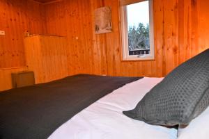 uma cama num quarto de madeira com uma janela em Thingvellir Cabin/Chalet em Selfoss