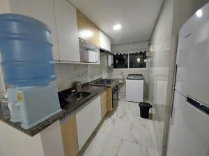 a large white kitchen with a large bucket on the counter at MAKARANDUBA BEACH 304 - Piscinas Naturais e Coração de Porto in Porto De Galinhas