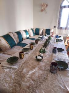 a long table with plates and bowls on it at Riad ma bonne étoile in Kasr Bounou