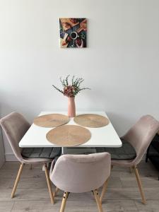 a white table with chairs and a vase on top at Angela Nordic apartment. in Suceava +11 photos