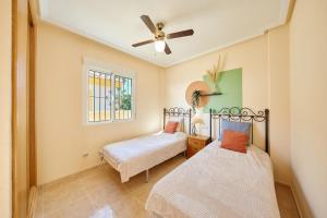 two beds in a room with a ceiling fan at Villa con vistas al mar in Alicante