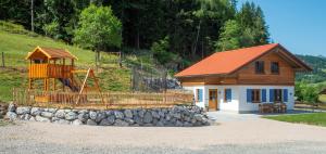 ein kleines Gebäude mit einem Spielplatz und einem Haus in der Unterkunft Weißenbach´s Ferienhof in Wertach