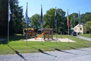 een park met een speeltuin met vlaggen in het gras bij Camping De Chênefleur in Tintigny