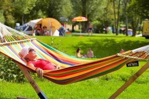 una donna sdraiata su un'amaca in un parco di Camping De Chênefleur a Tintigny