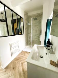a bathroom with a white sink and a mirror at La Maison Hugo in Montreuil
