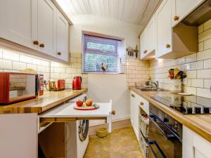 una cucina con armadi bianchi e un tavolo con mele di 3 bed property in Bath 79174 a Chilcompton
