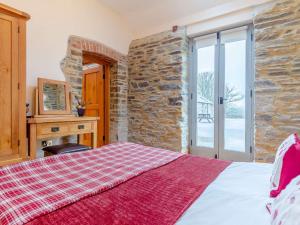 a bedroom with a bed and a stone wall at 1 bed property in Launceston 81332 in Saint Giles on the Heath