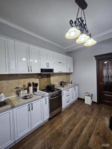 una cucina con armadi bianchi e piano cottura di Эсалу Гостиный Дом a Privokzalʼnoye