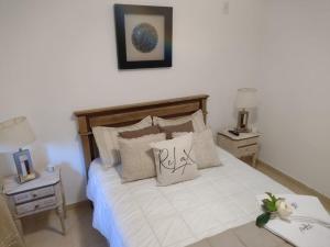 1 dormitorio con 1 cama con sábanas y almohadas blancas en Casa MAGNOLIA en Chacras de Coria