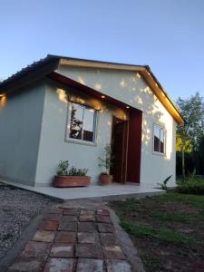una pequeña casa blanca con macetas delante de ella en Casa MAGNOLIA en Chacras de Coria
