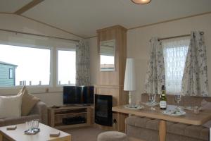 a living room with a couch and a tv at Caravan 20 Neptune Caravan Park in Tywyn