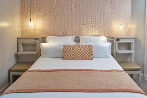 a bed with white pillows and a orange wall at H&ocirc;tel Vic Eiffel in Paris