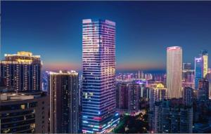 une vue éclairée sur les toits de la ville avec un grand bâtiment dans l'établissement Millenia Executive Apartment - Guangzhou East Railway Station Zhujiang New Town Branch, à Canton