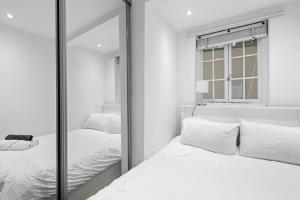 a mirror in a bedroom with two beds at Londwell, Sloane Square Gem, Private Terrace Suite in London