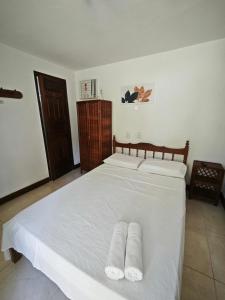 Un dormitorio con una cama blanca con toallas. en Pousada Villa Graciela, en Ilhéus