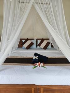 ein Bett mit einem Baldachin mit Blumen drauf in der Unterkunft The Gana Ubud by Guru experience in Ubud
